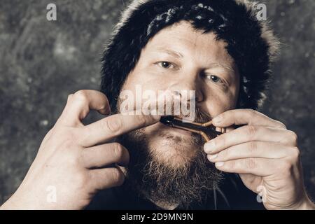 Uomo maturo in pelliccia cappello che gioca ebrei arpa ritratto studio Foto Stock