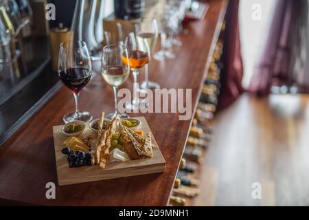 Degustazione di vini con spuntini. Varietà di formaggi, olive mediterranee, sottaceti, prosciutto di Parma, pomodori, carciofi e vino in calici Foto Stock