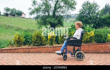 Donna anziana in una sedia a rotelle Foto Stock