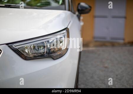 Auto bianca con luci abbassate, di fronte alla casa sul vialetto. SUV e mediterraneo casa ghiaia vialetto Foto Stock