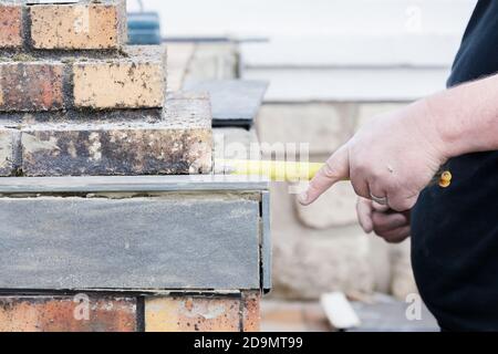 L'installatore le misure e le mette segni per il taglio e la posa di un tile Foto Stock