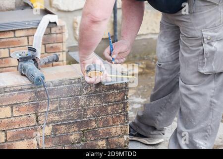 L'installatore le misure e le mette segni per il taglio e la posa di un tile Foto Stock