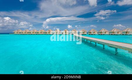 Paesaggio panoramico della spiaggia Maldive. Panorama tropicale, resort di lusso con ville d'acqua con molo o molo in legno. Sfondo di destinazione di viaggio di lusso Foto Stock