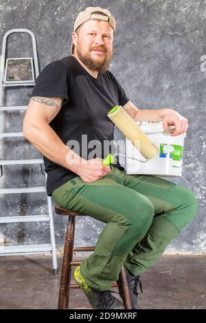 Gioioso caposquadra in pantaloni verdi con studio di utensili da lavoro verticale Foto Stock