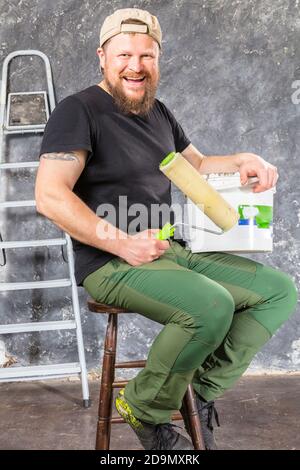 Gioioso caposquadra in pantaloni verdi con studio di utensili da lavoro verticale Foto Stock