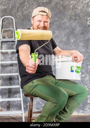 Gioioso caposquadra in pantaloni verdi con studio di utensili da lavoro verticale Foto Stock