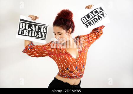 Molto felice ragazza sorridente festeggiando e ballando tenendo in mano due manifesti del Black Friday che sta tenendo in mano. Giovane donna con pelle bianca a Foto Stock