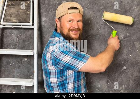 Gioioso caposquadra in pantaloni verdi con studio di utensili da lavoro verticale Foto Stock