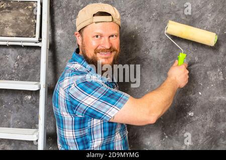 Gioioso caposquadra in pantaloni verdi con studio di utensili da lavoro verticale Foto Stock