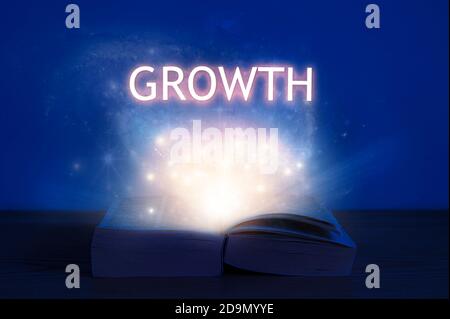 Apri il libro con iscrizione di crescita. Luce proveniente dal libro aperto con la crescita delle parole. Foto Stock