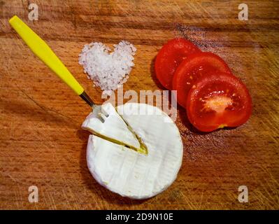 Pomodori affettati con formaggio a muffa bianco e sale di pietra a forma di cuore Foto Stock