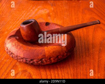 Vecchio tubo di legno in un posacenere di legno su sfondo di legno Foto Stock