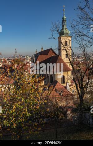 Chiesa di nostra Signora vittoriosa (Santuario del Bambino Gesù di Praga), una vista posteriore dai giardini sulle pendici della collina di Petřín. Scena autunnale con cielo blu. Foto Stock