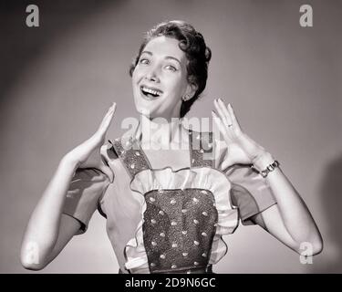 1950 ORGOGLIOSA CASALINGA BRUNA SORRIDENTE INDOSSANDO GREMBIULE FACENDO GESTO DI POLLICE NASCOSTO GUARDANDO LA FOTOCAMERA - G2204 DEB001 HARS CASALINGA FELICITÀ CASALINGHE ALLEGRO ECCITAZIONE ORGOGLIO CASALINGHE SORRIDE GIOIOSO NASCOSTO DEB001 MID-ADULT MID-ADULT DONNA NERO E BIANCO ETNIA CAUCASICA VECCHIO STILE Foto Stock