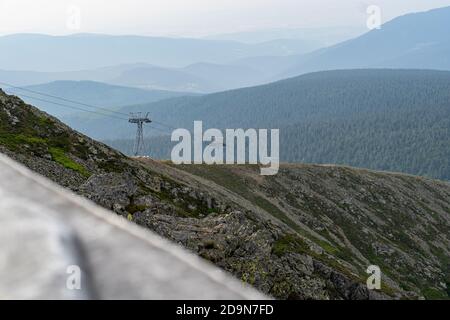 Un ascensore per slittino in montagna, cime di montagna nebbie sullo sfondo. Foto Stock