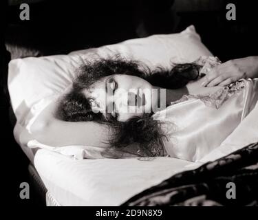 ANNI '20 1930 ATTRAENTE GIOVANE DONNA LUNGO CAPELLI RICCI BRUNETTE TRANQUILLAMENTE DORMENDO SDRAIATO SULLA SCHIENA CON LA TESTA IN UN ANGOLO DI IL SUO BRACCIO - N363 HAR001 HARS TESTA E SPALLE ALTO ANGOLATURA IN RICCI SU CONCETTUALE CAPELLI LUNGHI ELEGANTE RIPOSANTE ATTRAENTE RELAX RIPOSO GIOVANE DONNA ADULTA IN BIANCO E NERO ETNIA CAUCASICA HAR001 VECCHIO STILE Foto Stock