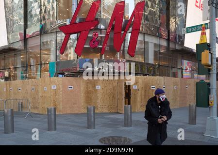 Un uomo che indossa una maschera esce da un negozio H&M a bordo in Times Square. Foto Stock