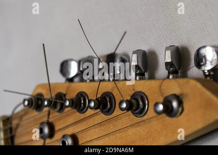 Primo piano di un pegbox di una chitarra elettrica su uno sfondo grigio chiaro Foto Stock