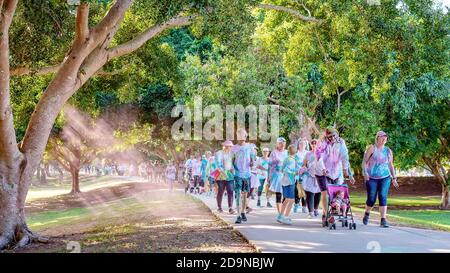 MACKAY, QUEENSLAND, AUSTRALIA - GIUGNO 2019: La polvere rosa riempie l'aria come le famiglie iridate in costume non identificate camminano felicemente in Color Frenzy Fun Run Foto Stock