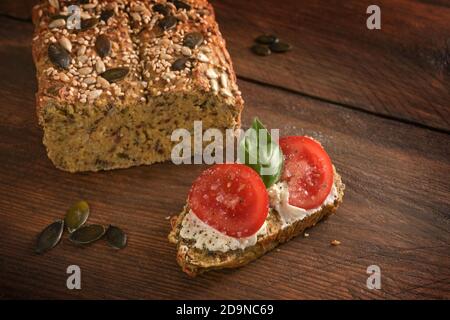 Pomodori, basilico e formaggio spalmabile su pane proteico fatto in casa a base di farina di lupino, crusca di avena e semi di zucca, dimagrimento con dieta a basso contenuto di carboidrati o chetogeni, da Foto Stock