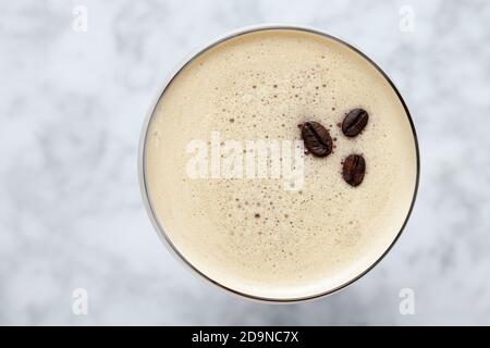 Vista dall'alto di un espresso Martini guarnito con tre caffè fagioli su un tavolo di marmo Foto Stock