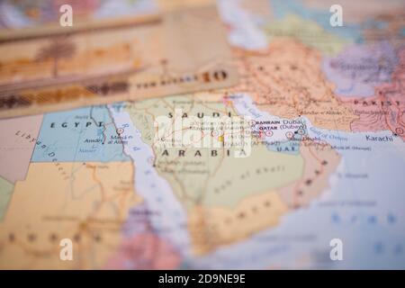 Dieci riyals fattura sopra l'Arabia Saudita su un colorato e. Mappa sfocata dell'Asia occidentale Foto Stock