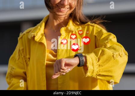 Donna con smartwatch sempre come piace. Social media e concetto di comunicazione. Icone di notifica di simili. Foto Stock