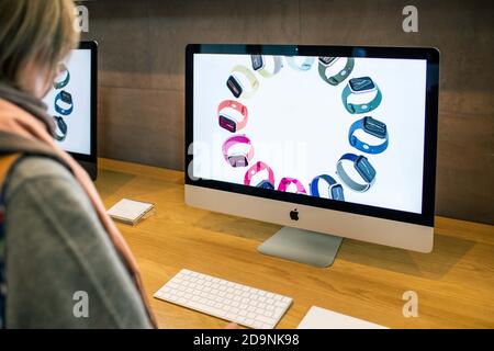 Parigi, Francia - 16 novembre 2019: Vista laterale della donna che guarda i più recenti computer Apple iMac 27 21 pollici personal computer con pubblicità sullo schermo 5k per il nuovo orologio Apple con più band Foto Stock