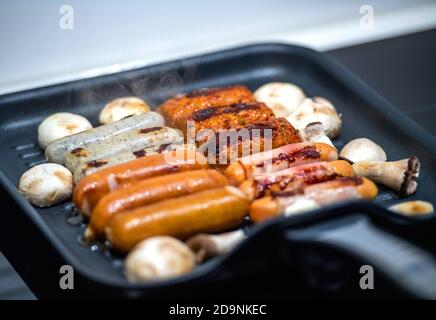 Vista dall'alto di un ampio piatto grigliato con più tipi di Salsicce tedesche fritte Foto Stock