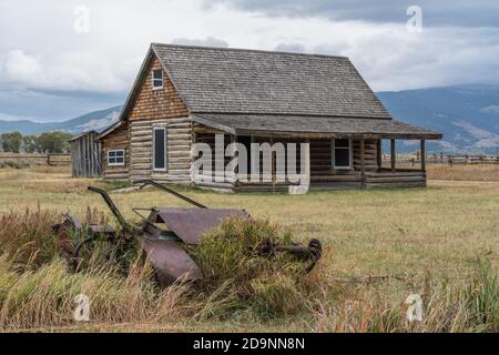 Vecchie macchine agricole e la casa di tronchi sulla casa Andy Chambers sulla Mormon Row nel Grand Teton National Park nel Wyoming, Stati Uniti. Foto Stock