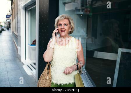 signore che parlano al telefono con le loro borse della spesa Foto Stock