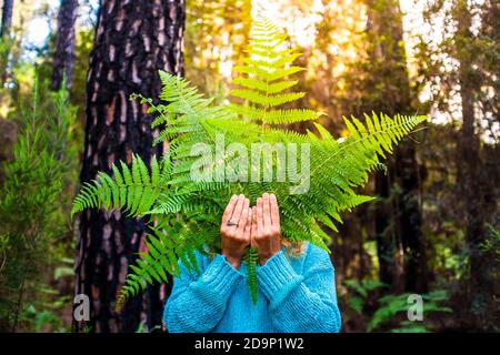 Ritratto di persone irriconoscibili nascoste da grandi foglie dalla natura forest - concetto di giorno della terra e ambiente naturale all'aperto attività per il tempo libero - nessuna deforestazione e salvare lo stile di vita del pianeta Foto Stock