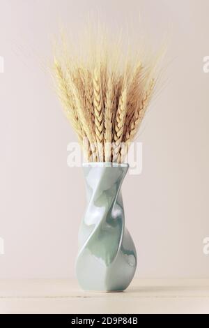 Orecchie gialle di grano in un vaso su sfondo neutro con spazio di copia. Foto Stock