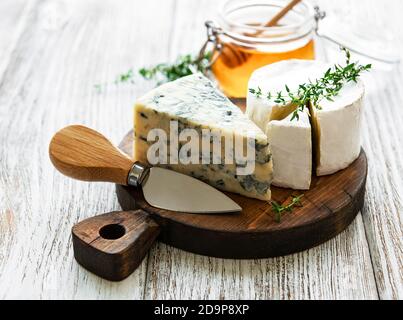 Vari tipi di formaggio, formaggio blu, preda, camambert e miele su un tavolo di legno Foto Stock