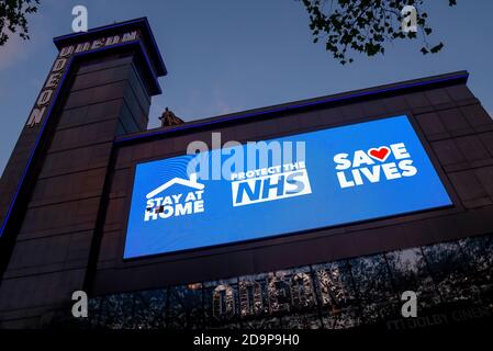 Cinema Odeon a Leicester Square, Londra, Regno Unito, durante il blocco COVID 19 con slogan governativi. Rimani a casa, proteggi l'NHS, salva la vita Foto Stock