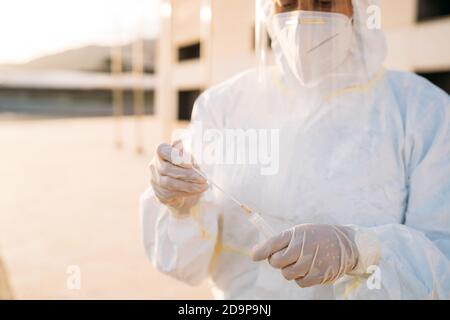 Ritratto di una giovane operatrice medica usa un test PCR su una persona all'interno di un'auto per determinare la presenza o l'assenza del Covid-19. Foto Stock