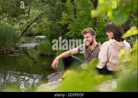 Data di bella giovane coppia seduta sulla roccia. Relazioni sensibili di belle persone. Viaggio al canyon carsico vicino al torrente. I capelli noccioli Foto Stock