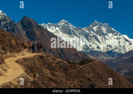 Il monte Everest si trova sopra un gruppo di escursionisti occidentali Il percorso tortuoso per il campo base nel Nepal Himalaya Foto Stock