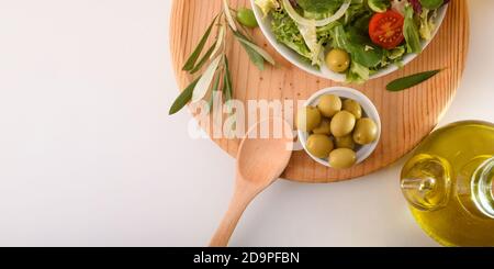 Insalata mediterranea con prodotti freschi e olio d'oliva su una panca bianca da cucina. Vista dall'alto. Composizione orizzontale. Foto Stock