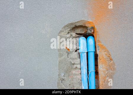 seppellire un tubo in pvc nella parete di cemento con copyspace sulla sinistra Foto Stock