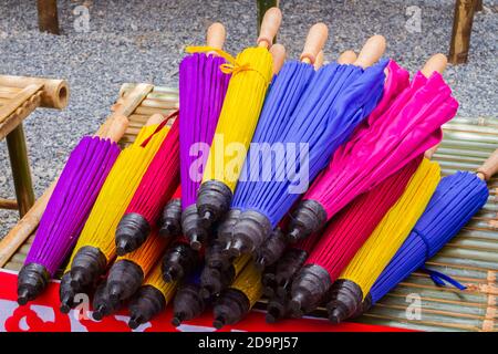 Colorato ombrello thailandese ripiegato di bambù venduto sul mercato. Foto Stock