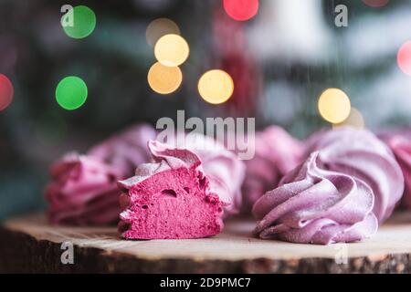 Primo piano di zephyr o marshmallow in polvere di zucchero su legno con fondo bokeh astratto. Ribes nero, marshmallows di mirtillo. Foto Stock