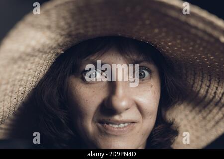 Allegra donna di 40 anni in un cappello largo-brimmed primo piano visualizza ritratto studio Foto Stock