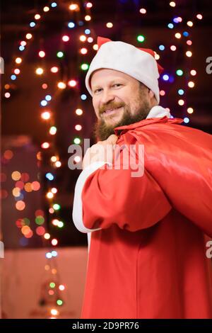 Uomo bearded vestito in costume di Babbo Natale con studio di regali ritratto con luci sullo sfondo Foto Stock