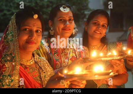 Tre belle Signore sorridenti indossare abiti tradizionali e preparazione lampade ad olio leggero su Diwali Festival (Lighting Festival) a Beawar, Rajasthan. Foto Stock