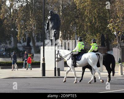 La polizia metropolitana a cavallo passa accanto alla statua di Winston Churchill in Parliament Square, Londra, il terzo giorno di un blocco nazionale di quattro settimane per l'Inghilterra per combattere la diffusione di Covid-19. Foto Stock