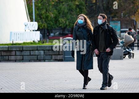 Coppia indossando maschera e camminando in città con 2020 Simbolo sullo sfondo durante l'epidemia di Covid o Coronavirus Foto Stock
