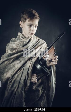 Tenn ragazzo vestito in camouflage abito con una pistola a giocare ritratto in studio soldier Foto Stock