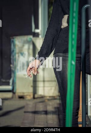 Ragazza che tiene una sigaretta in mano Foto Stock