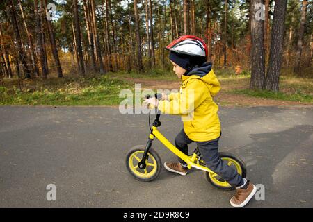 Carino ragazzo in casualwear e casco protettivo a cavallo bicicletta da equilibratura Foto Stock